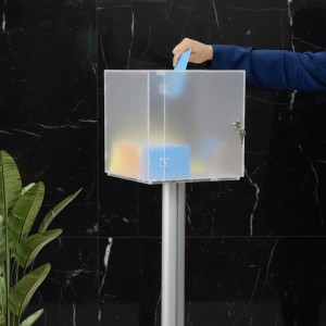 mano intenta a inserire foglio azzurro dentro a una urna in plexiglass da terra - DANIELI
